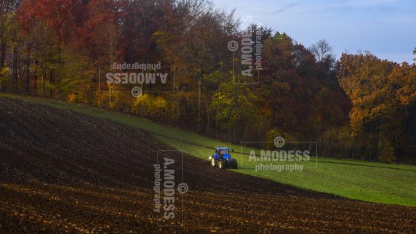 Blå traktor plöjer åker på hösten