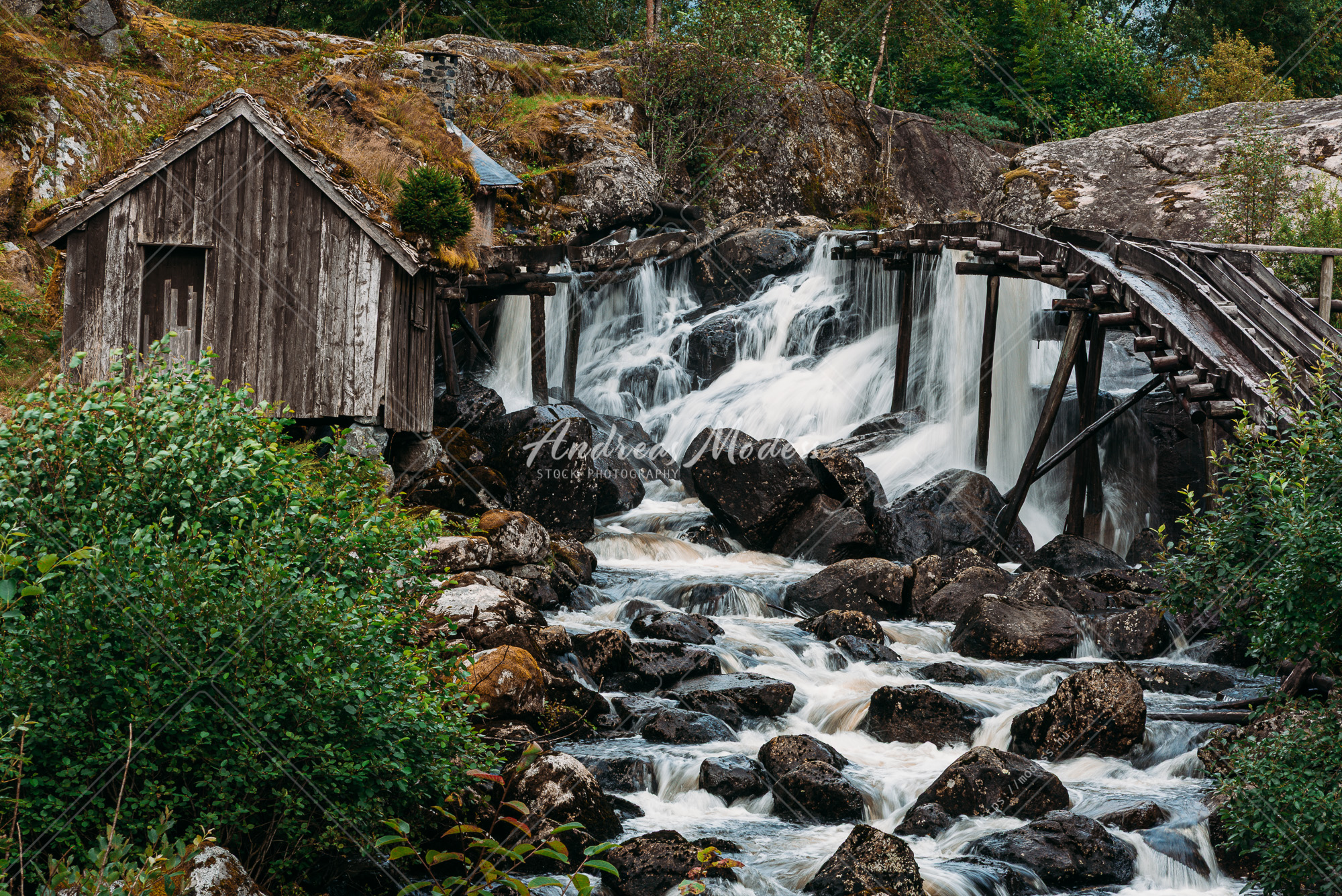 Ett litet trähus står bredvid en porlande flod.